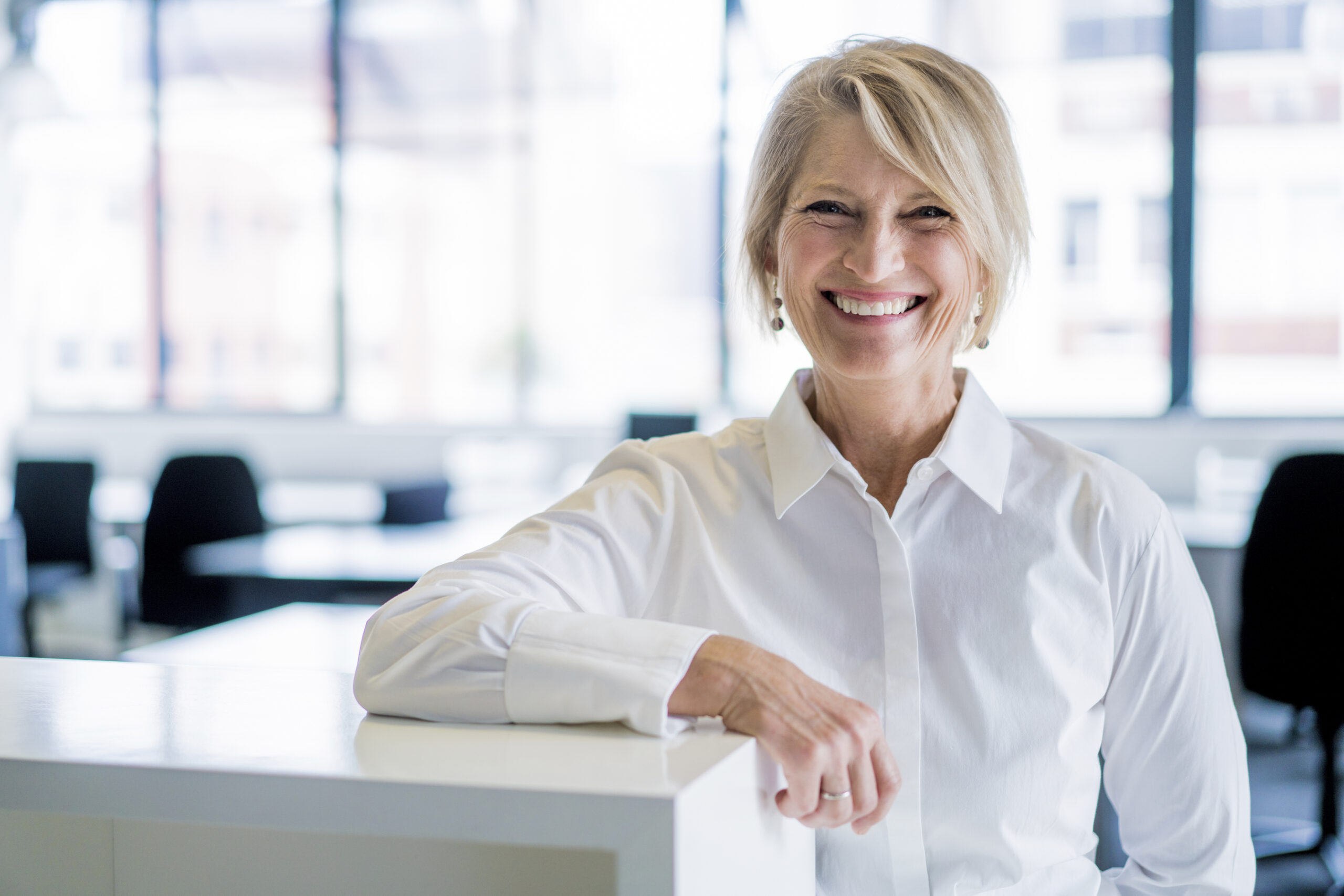 Happy businesswoman leaning on cubicle in office