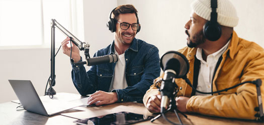 Happy radio presenter interviewing a podcast guest in a studio
